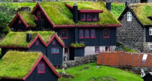 Faroe Adaları'nda yeşil çim çatılı geleneksel evler ve dramatik doğal manzara