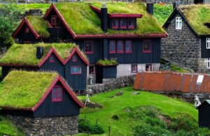 Faroe Adaları'nda yeşil çim çatılı geleneksel evler ve dramatik doğal manzara