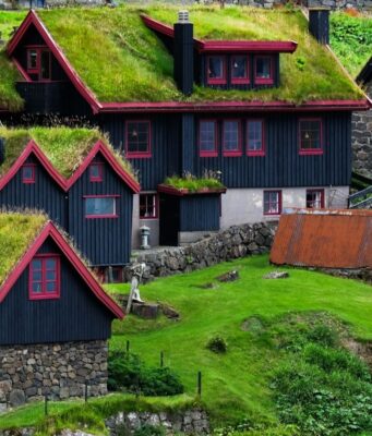 Faroe Adaları'nda yeşil çim çatılı geleneksel evler ve dramatik doğal manzara