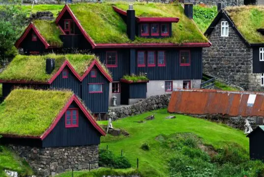 Faroe Adaları'nda yeşil çim çatılı geleneksel evler ve dramatik doğal manzara