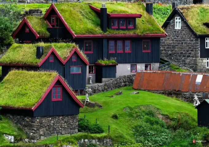 Faroe Adaları'nda yeşil çim çatılı geleneksel evler ve dramatik doğal manzara