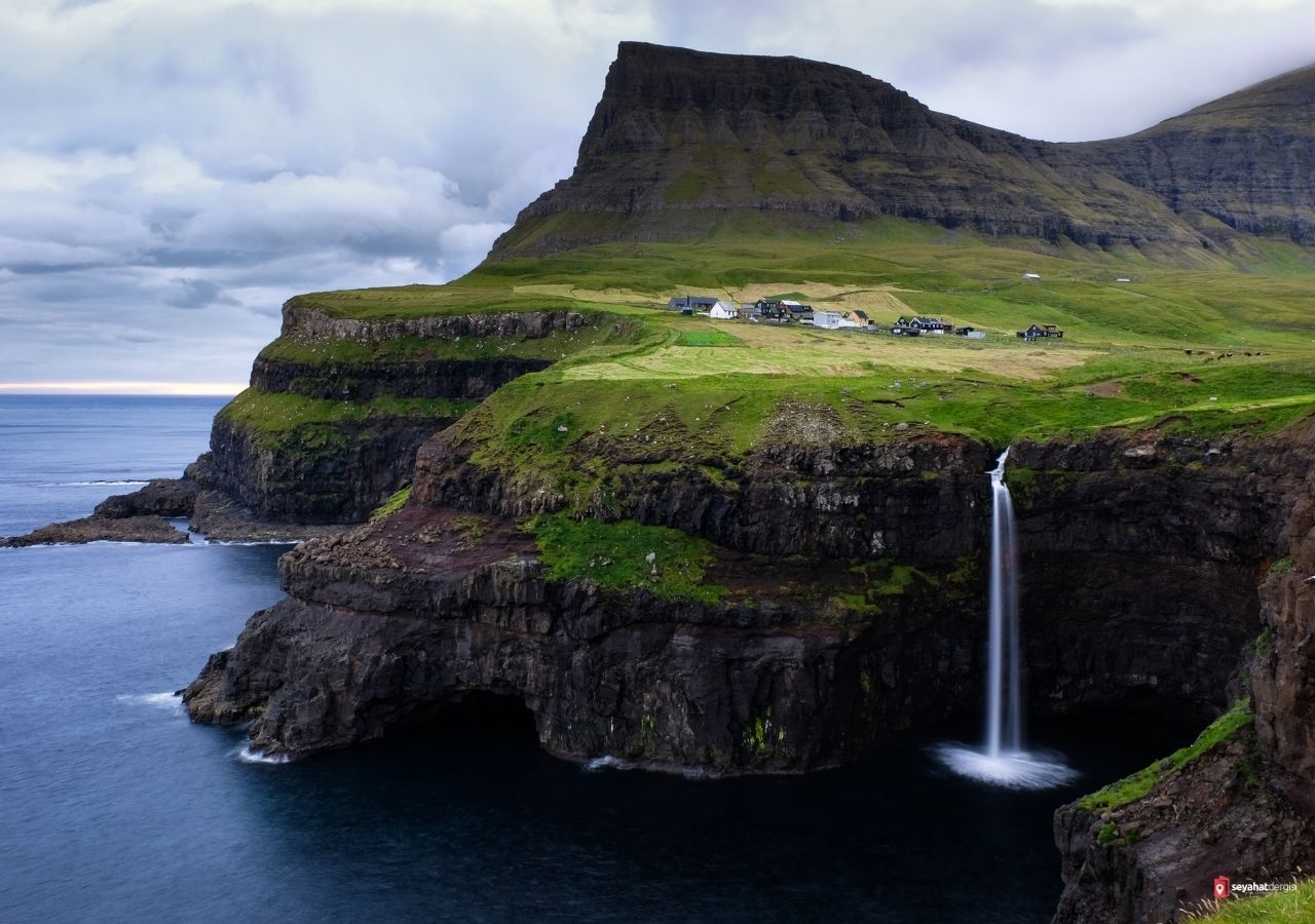 Gásadalur köyündeki çim çatılı evler ve Múlafossur Şelalesi manzarası Faroe Adaları